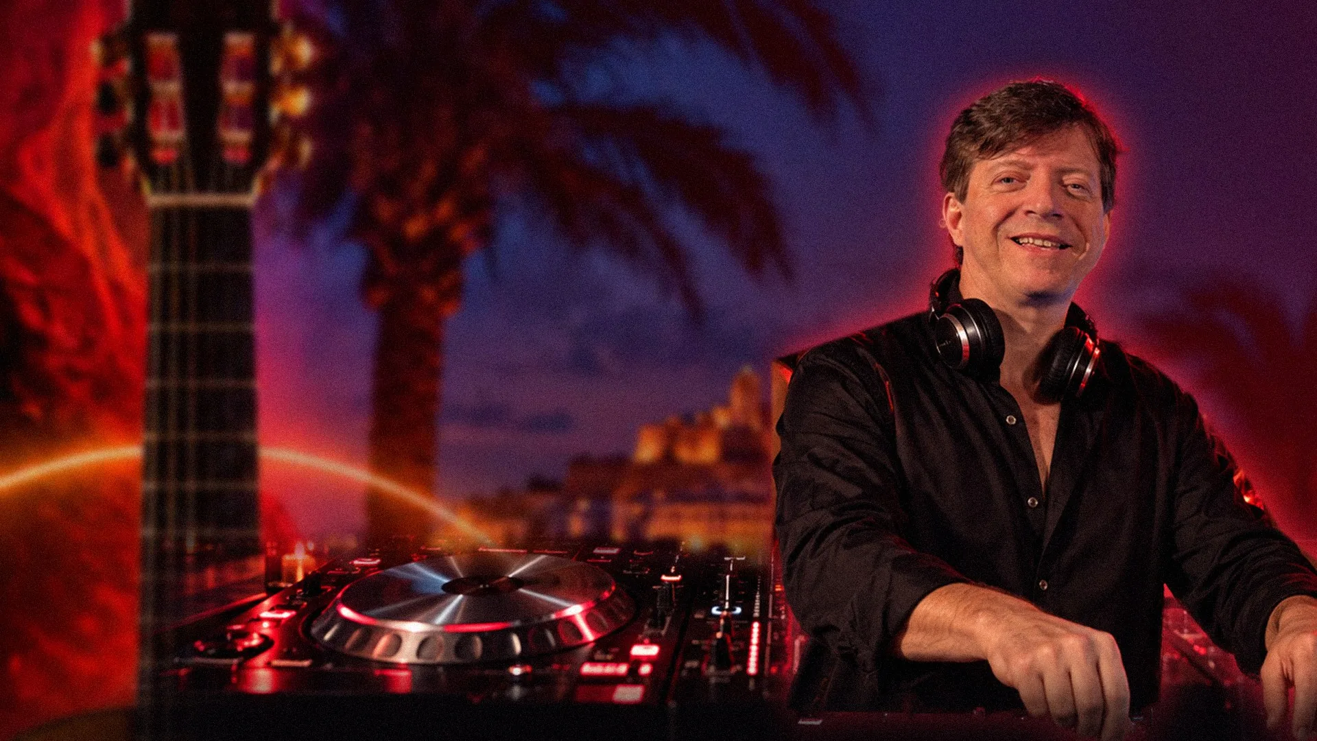 HUGOB1 smiling at the decks under an Ibiza night sky, a flamenco guitar glowing behind him